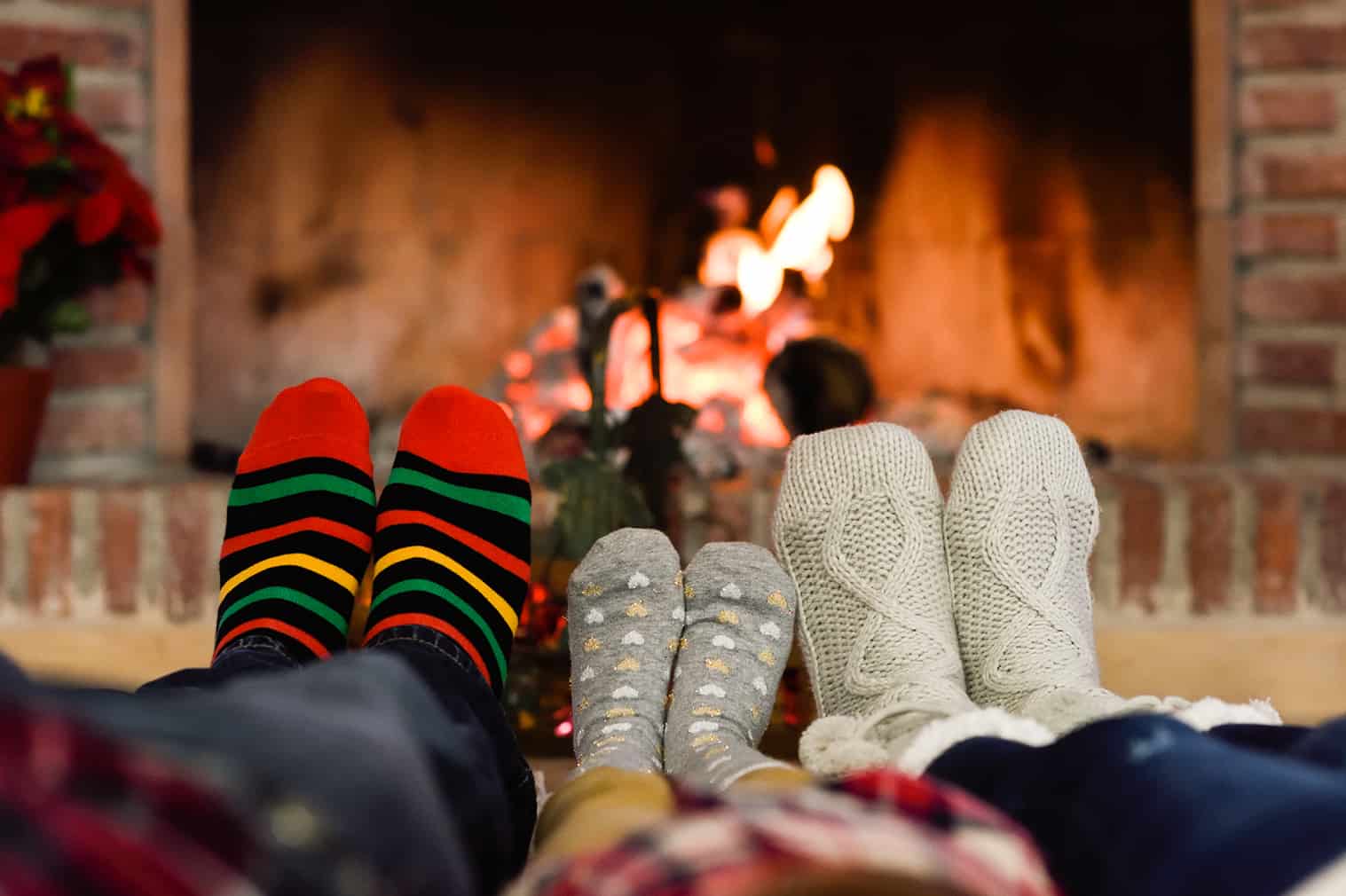Feet in Christmas socks near fireplace